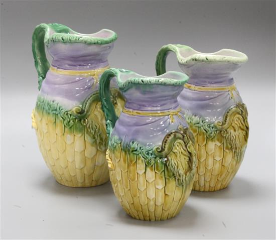 Three Majolica jugs and a pair of copper candlesticks
